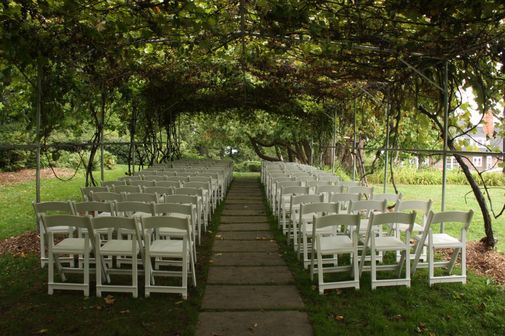 white chairs set up under the grape arbor for ceremony