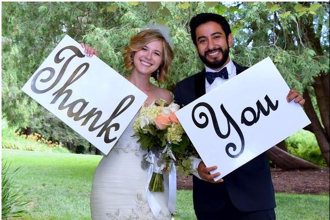 bride and groom hold thank you signs