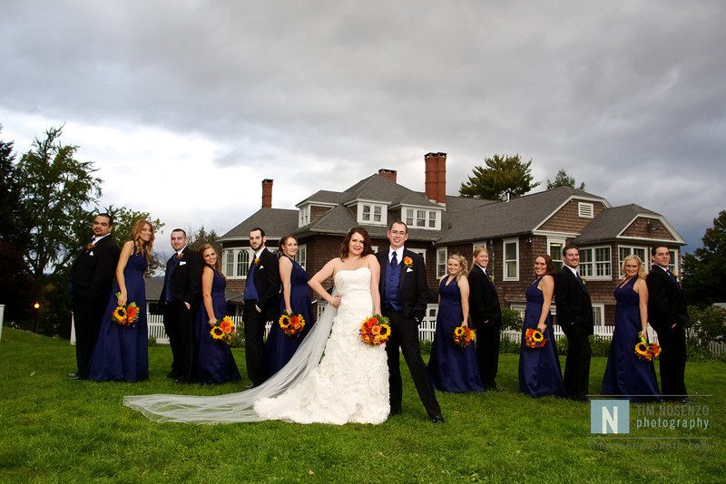 wedding party posing under gray sky on the lawn with tarrywile mansion in the background