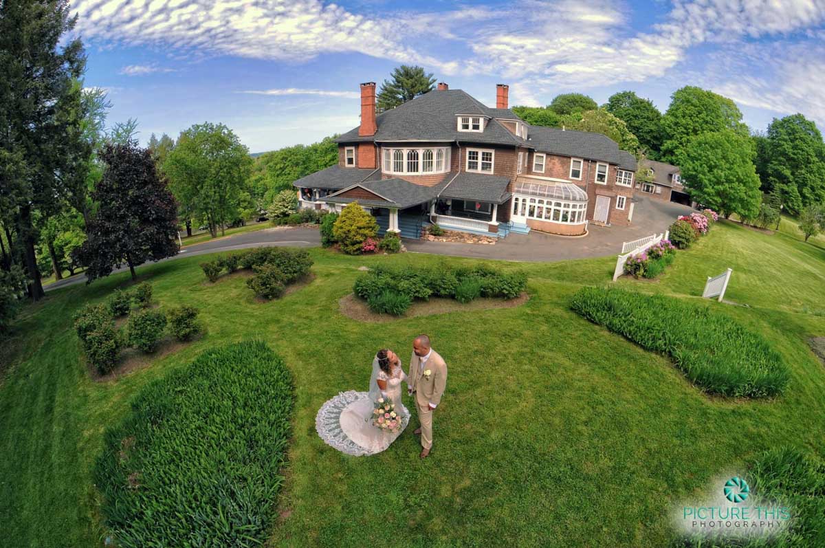 a-victorian-era-wedding-aerial-photo-of-couple-with-mansion