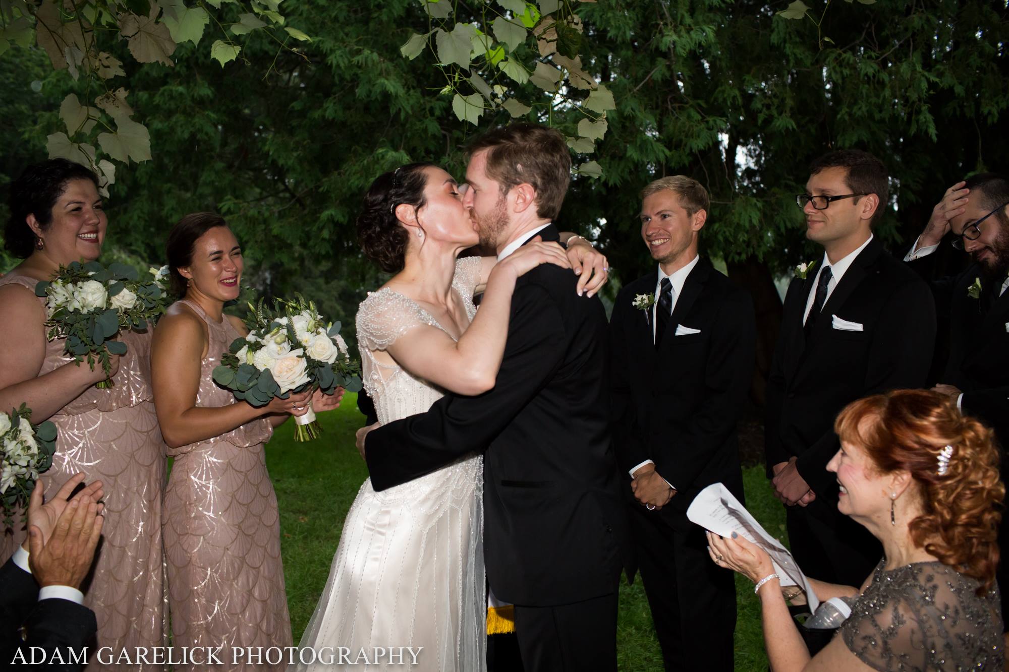 bride and groom kiss under the grape arbor