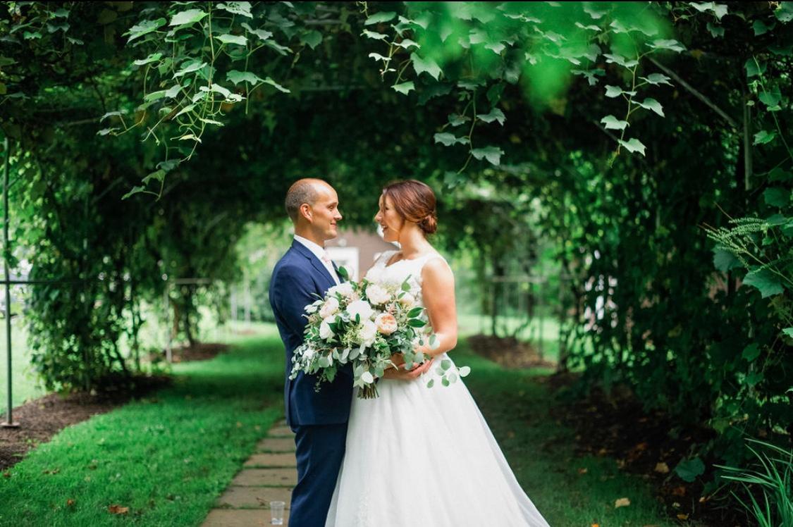 bride and groom facing each other under the grape arbor