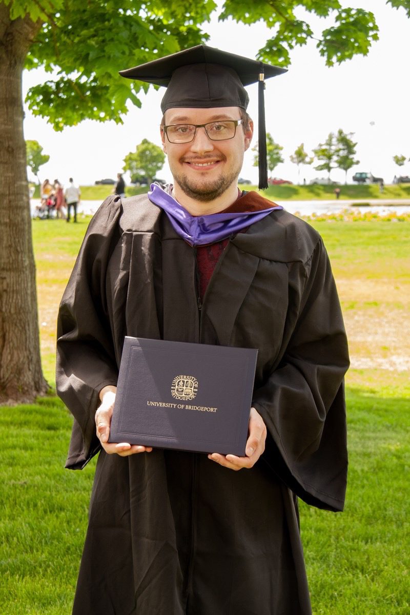 zach-holding-diploma-in-cap-gown