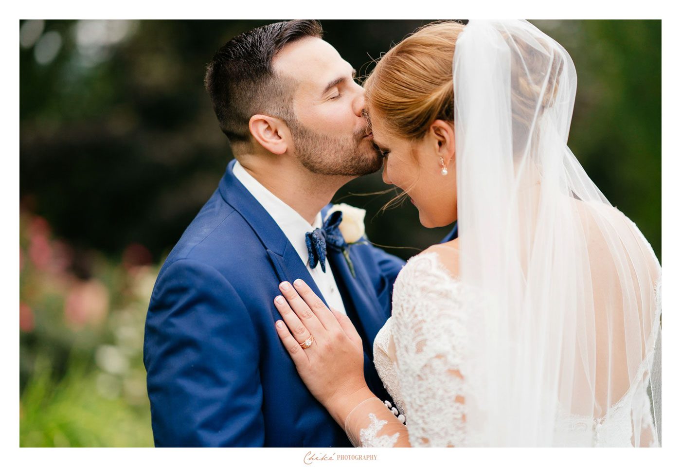 college groom kissing his brides forehead